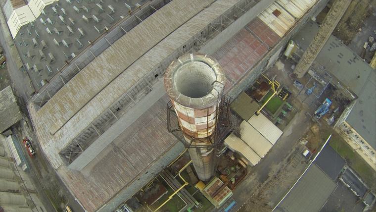 Vedere din aer a gurii unui coș de fum industrial din cărămidă, cu halele din jur